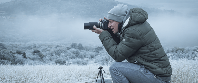 homme photographiant un paysage enneigé